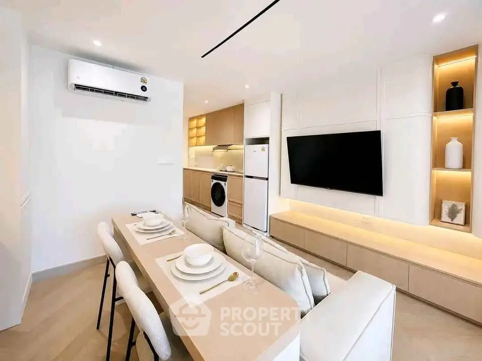 Modern open-plan living room with dining area, featuring sleek furniture and built-in appliances.