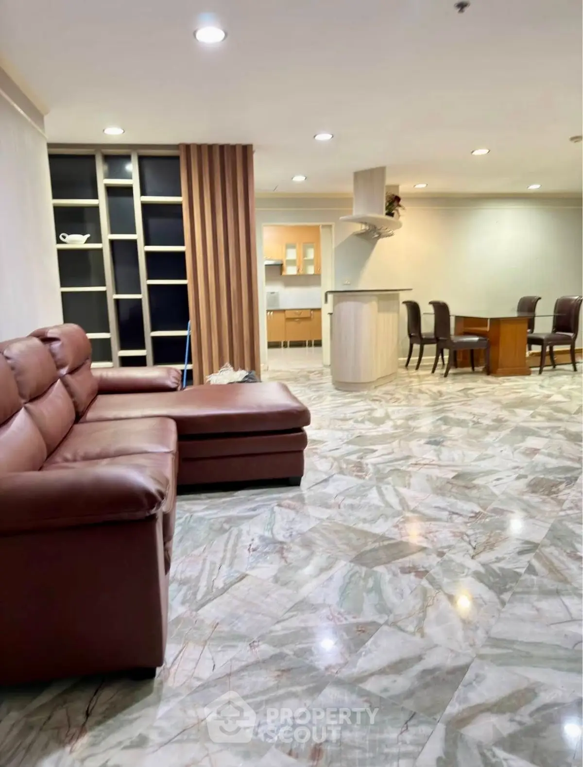 Spacious living room with elegant marble flooring and cozy leather sofa, open layout to dining area.