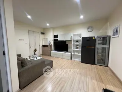 Modern living room with sleek furniture and wooden flooring, featuring a TV unit and stylish decor.