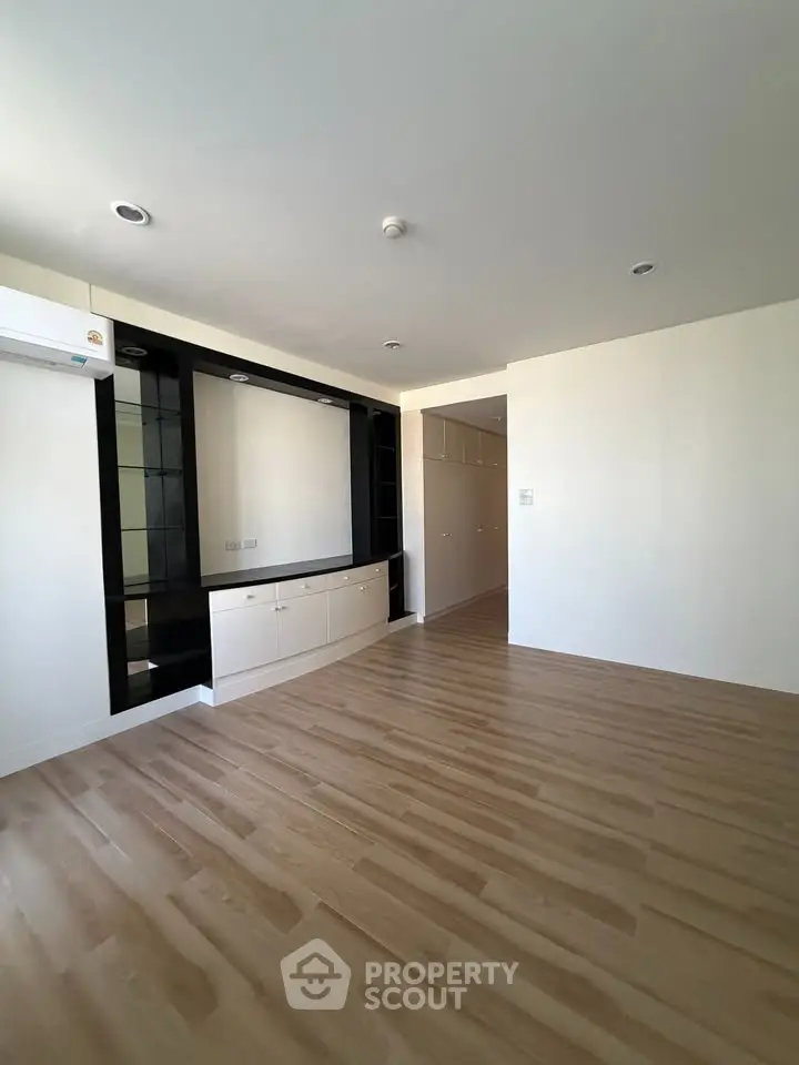 Spacious modern living room with sleek wooden flooring and built-in storage units.