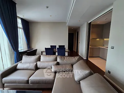 Spacious modern living room with elegant sofa and dining area, featuring large windows and stylish curtains.