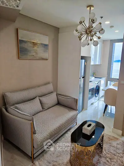 Modern living room with elegant sofa, stylish chandelier, and open kitchen layout with appliances.