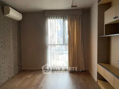 Spacious room with wooden flooring and large window, perfect for natural light.