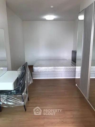 Modern bedroom with wooden flooring, mirrored wardrobe, and sleek furniture.