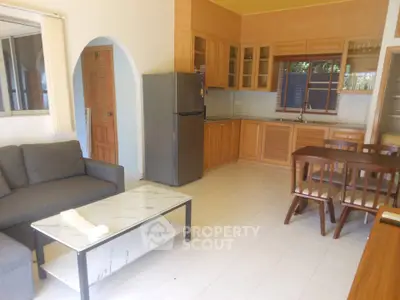 Spacious open-plan living room with modern kitchen and dining area, featuring sleek furniture and natural light.