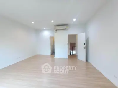 Spacious empty room with wooden flooring and air conditioning, perfect for customization.