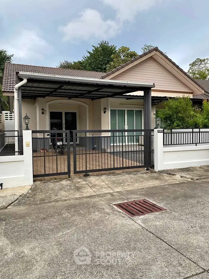 Charming single-story house with gated driveway and tiled roof in a serene neighborhood.