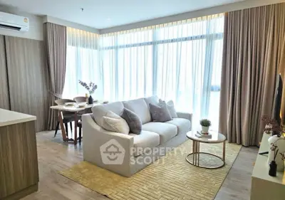 Modern living room with large windows, cozy sofa, and elegant decor in a bright apartment.
