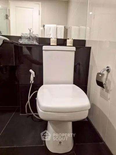 Modern bathroom with sleek black and white design featuring a contemporary toilet and elegant fixtures.