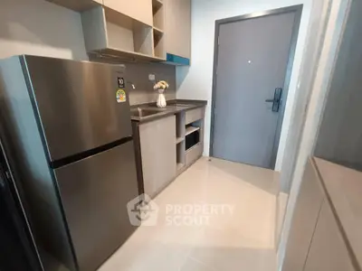 Modern compact kitchen with stainless steel fridge and sleek cabinetry