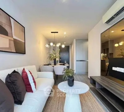 Modern living room with stylish decor and open dining area, featuring contemporary lighting and cozy seating.