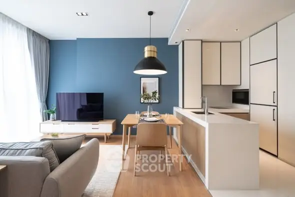 Modern open-layout living room and kitchen with stylish decor and natural light.