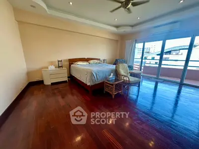 Spacious bedroom with hardwood floors and balcony access in modern apartment