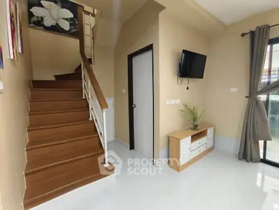 Modern interior with wooden staircase and wall-mounted TV in a cozy living space.