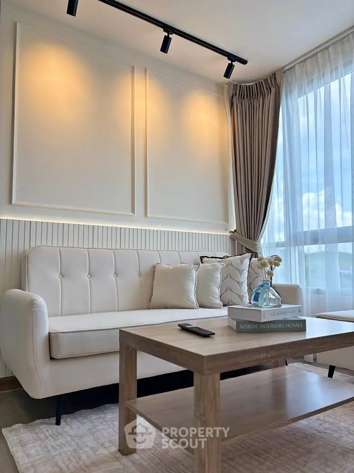 Elegant living room with cozy sofa and stylish decor, featuring large windows and natural light.