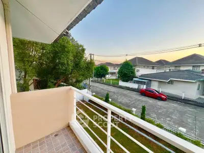 Charming balcony view overlooking suburban street with modern houses and a parked car at sunset.