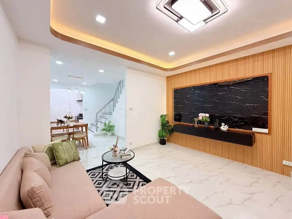 Modern living room with elegant decor and open dining area, featuring stylish lighting and sleek design.