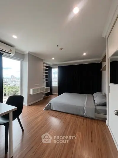 Modern bedroom with large windows and wooden flooring in a stylish apartment.