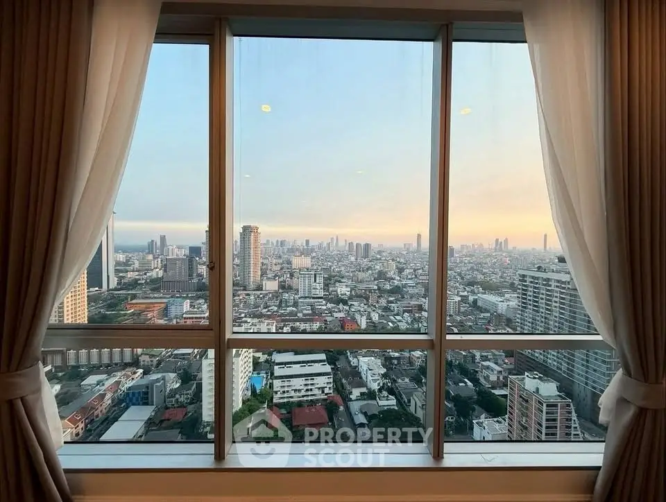 Stunning cityscape view from high-rise apartment window at sunset, showcasing urban skyline.