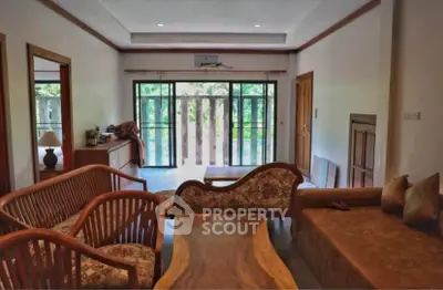 Spacious living room with elegant wooden furniture and large windows overlooking greenery