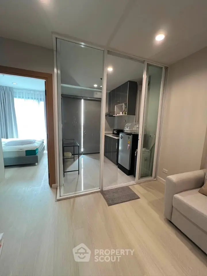 Modern apartment interior with open layout connecting living room and kitchen, featuring sleek design and natural light.