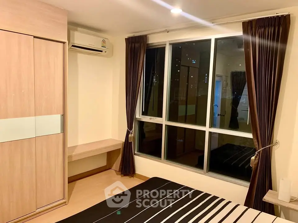 Cozy bedroom with large window and built-in wardrobe in modern apartment.