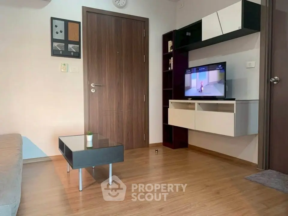 Modern living room with sleek furniture and wall-mounted TV in a cozy apartment setting.