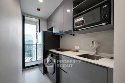 Modern compact kitchen with sleek appliances and city view balcony access.