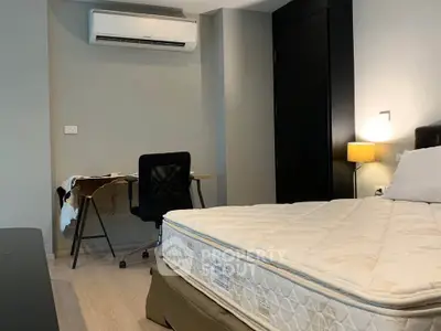 Modern bedroom with study area, featuring a comfortable bed and sleek desk under air conditioning.