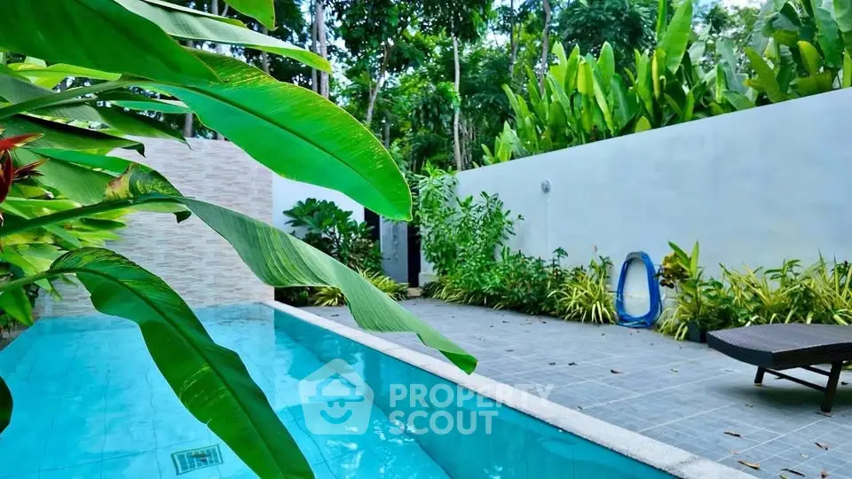 Luxurious tropical poolside oasis with lush greenery and serene ambiance.