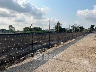 Expansive land plot with gravel path and fencing, ideal for development opportunities.