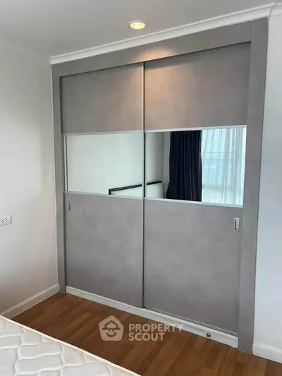 Modern bedroom with sleek sliding wardrobe and wooden flooring