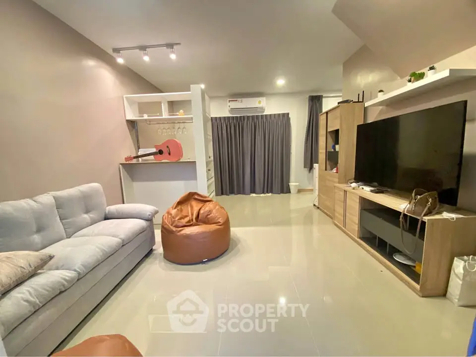 Modern living room with cozy sofa, bean bag, and large TV unit in stylish apartment.