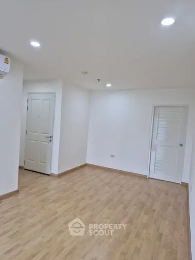 Spacious empty room with wooden flooring and white walls, ideal for customization.