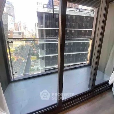 Modern balcony with glass railing offering cityscape views from high-rise apartment.