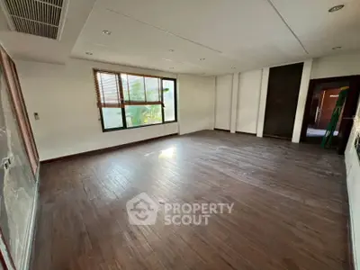 Spacious unfurnished room with wooden flooring and large windows, ideal for customization.