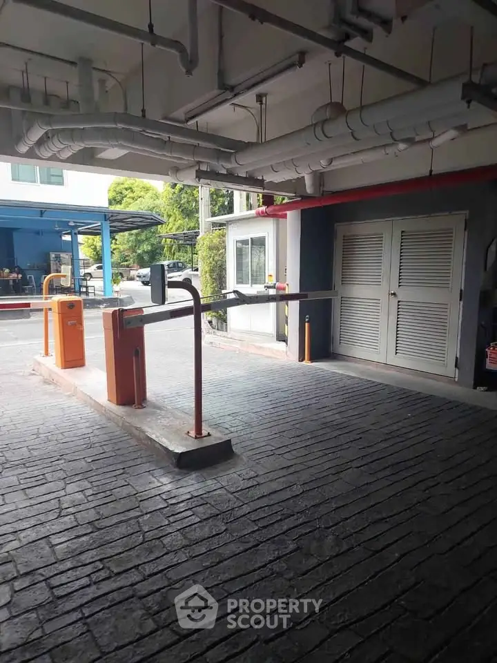 Secure parking entrance with automated barriers in modern residential complex.