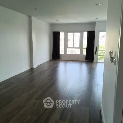 Spacious empty living room with large windows and wooden flooring