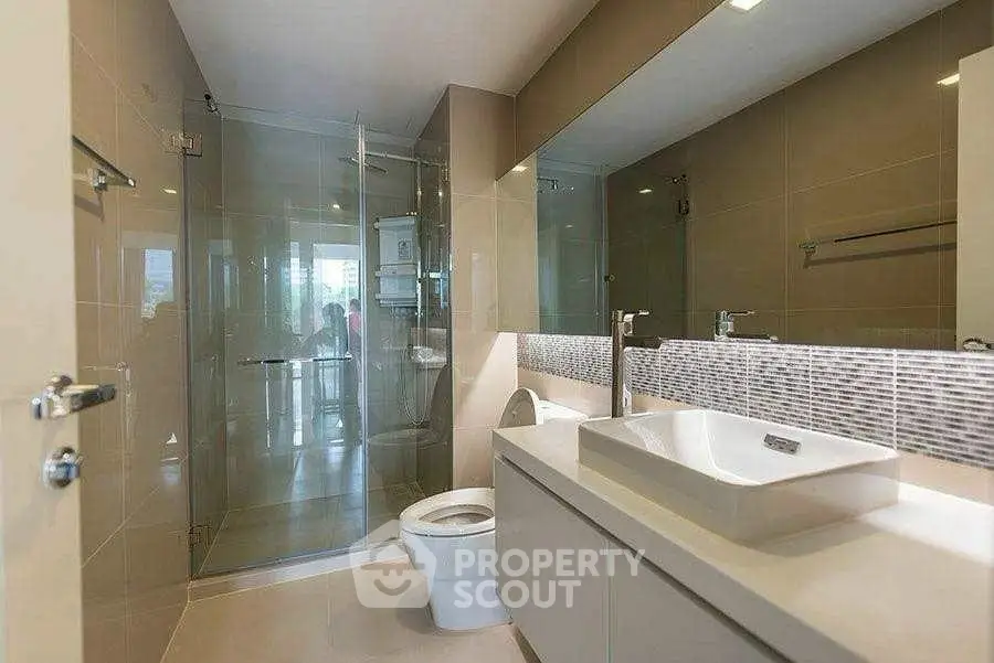 Modern bathroom with glass shower and sleek fixtures in luxury home.