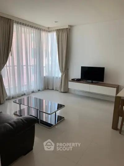 Spacious living room with ample natural light, modern furnishings, and elegant drapery, perfect for relaxation and entertainment.