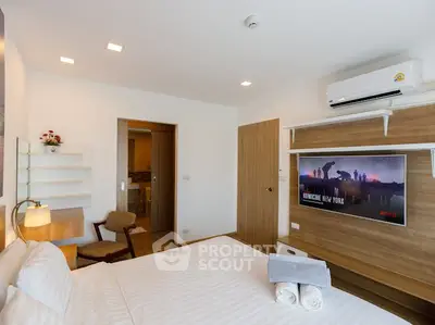Modern bedroom with wall-mounted TV and air conditioning, featuring a cozy bed and stylish decor.