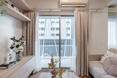 Stylish living room with modern decor and large window offering city view.