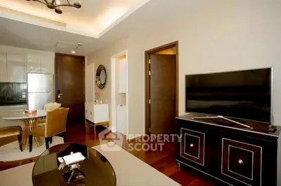 Modern living room with stylish furniture and open kitchen layout, featuring a sleek TV and dining area.