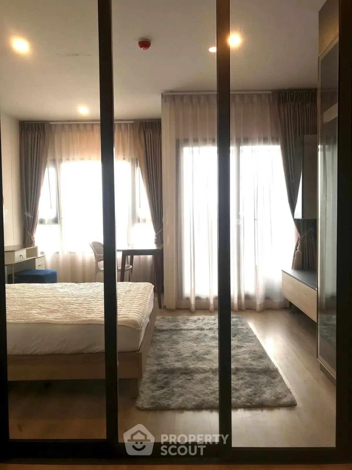 Modern bedroom with large windows and elegant decor in a stylish apartment.