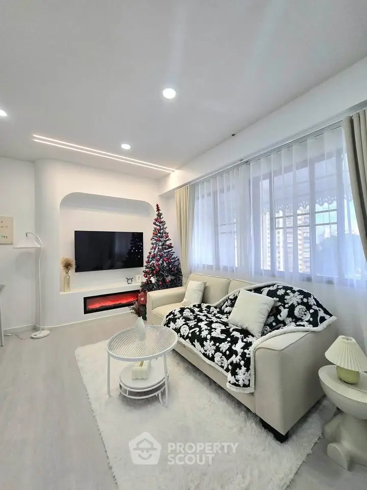 Elegant living room with modern decor and Christmas tree, featuring cozy seating and stylish lighting.