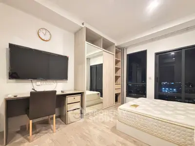 Modern bedroom with city view, featuring a sleek desk, wall-mounted TV, and spacious wardrobe.
