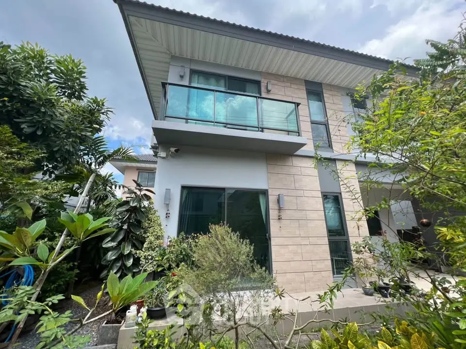 Modern two-story house with glass balcony and lush garden