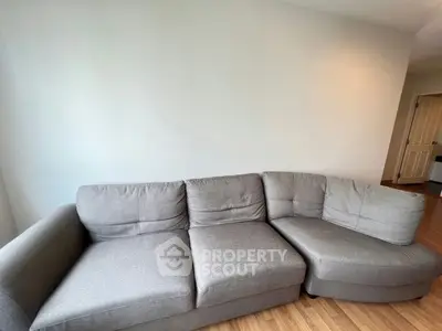 Spacious living room with modern gray sectional sofa and wooden flooring
