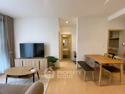 Spacious modern living room with dining area and TV, featuring elegant wooden furniture and natural light.