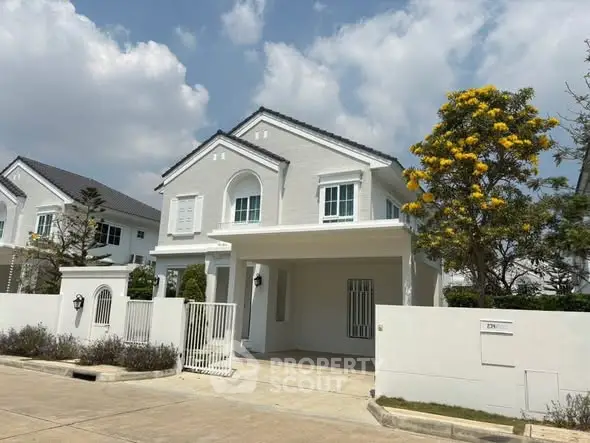 Charming white two-story house with a spacious driveway and lush greenery, perfect for family living.